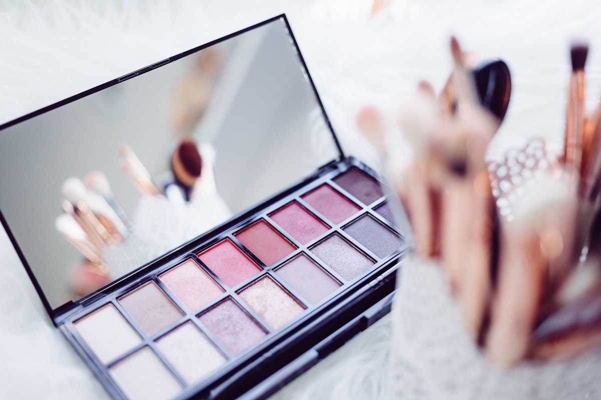 Pink makeup palette and brushes arranged on a dressing table